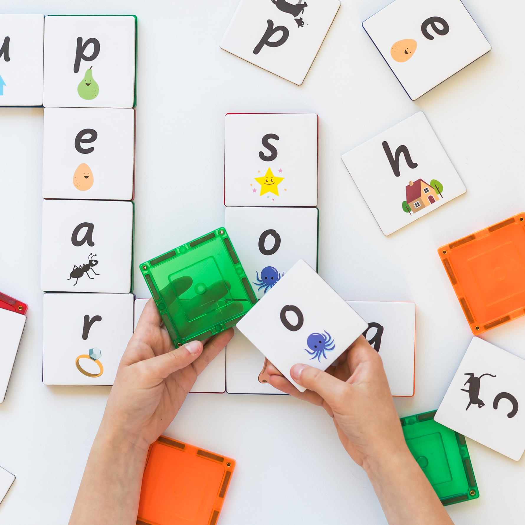 Hands showing putting an lowercase o tile topper onto a green magnetic tile