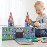 Boy sitting and playing with a castle made from magnetic tile toppers