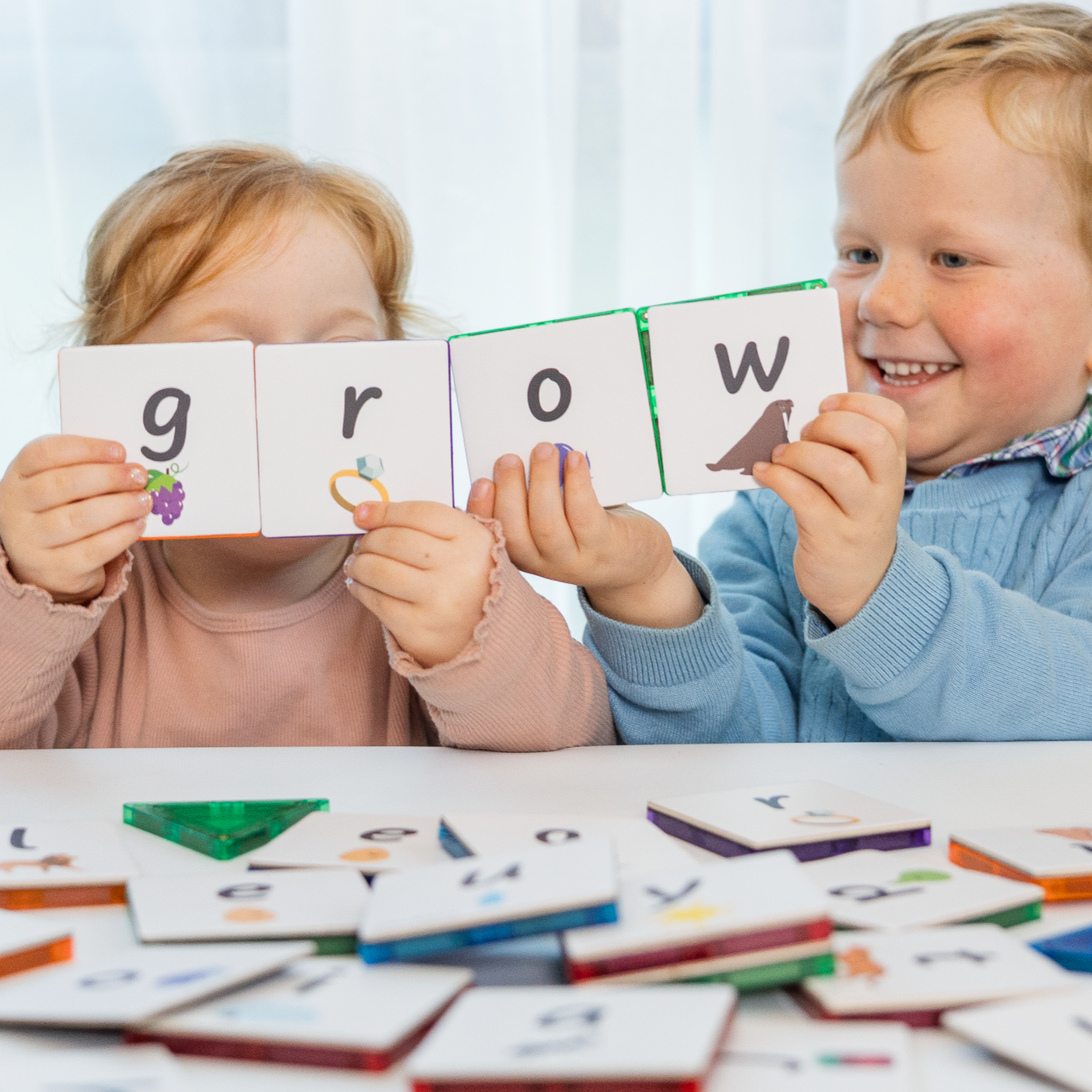 2 kids holding lowercase alphabet tile toppers that say grow 