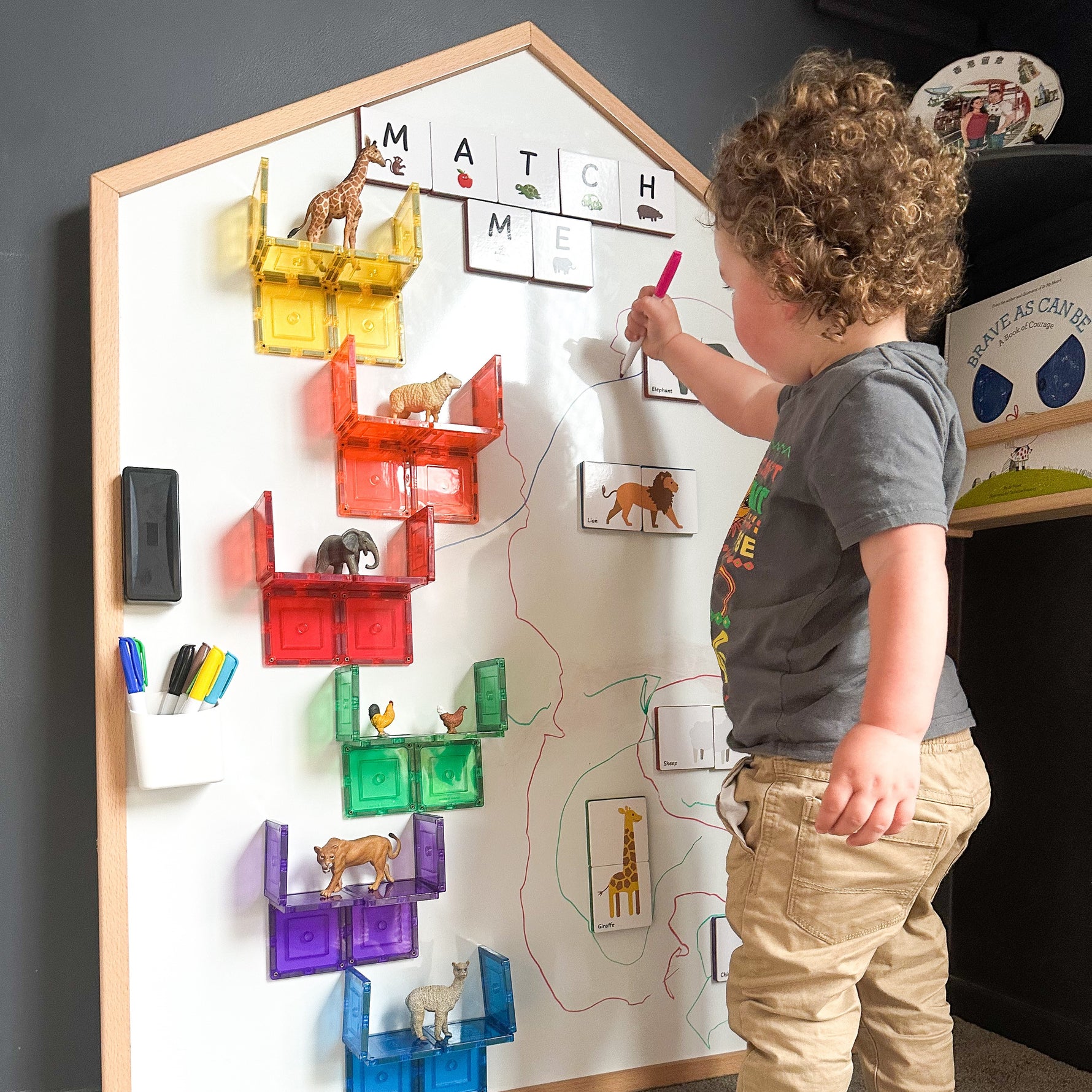 Child playing a match me game with magnetic tiles and toppers on a whiteboard of the Learn & Grow Toys Multi-Board