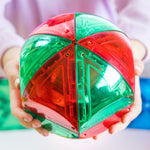 Child holding shiny red and green dome in their hands